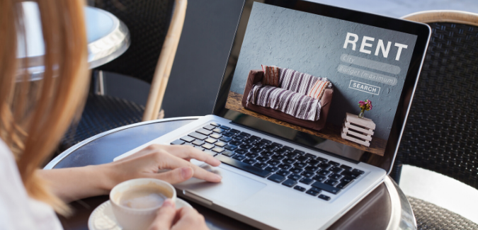 A photo of a woman searching for apartments on her laptop. 