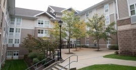 apartment courtyard of beige buildings with white windows and trees