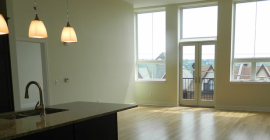 bright, well-lit living area with large windows and glass doors and kitchen counter